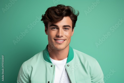smiling young man in green hoodie looking at camera on green background