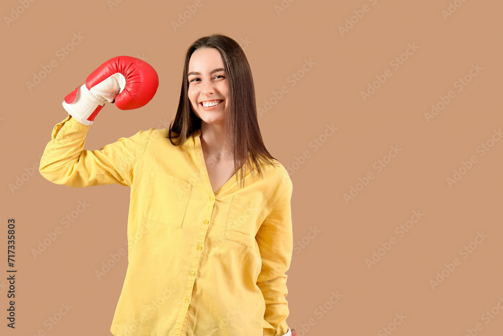 Beautiful young happy woman in boxing gloves on beige background. Women history month Beautiful young happy woman in boxing gloves on beige background. Women history month