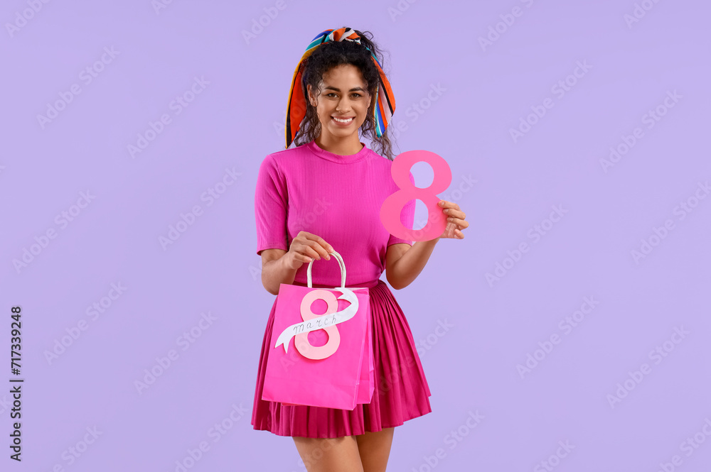 Fashionable African-American woman with figure 8 and shopping bags on lilac background. International Women's Day celebration
