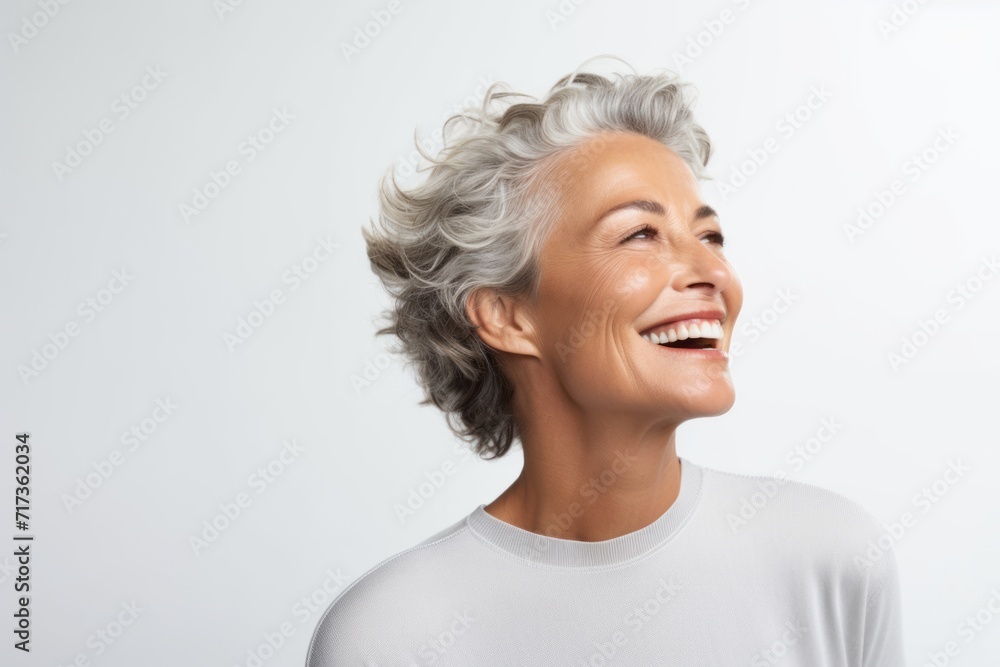 Portrait of happy senior woman laughing and looking up over gray background Portrait of happy senior woman laughing and looking up over gray background