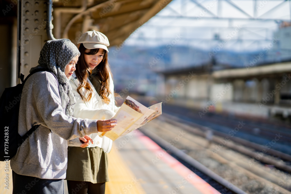 woman girl tourist Two Asian friends but different religions,They were looking at information about preparing to board the train at the train station,She is traveling in Japan. with fun, Japan travel woman girl tourist Two Asian friends but different religions,They were looking at information about preparing to board the train at the train station,She is traveling in Japan. with fun, Japan travel