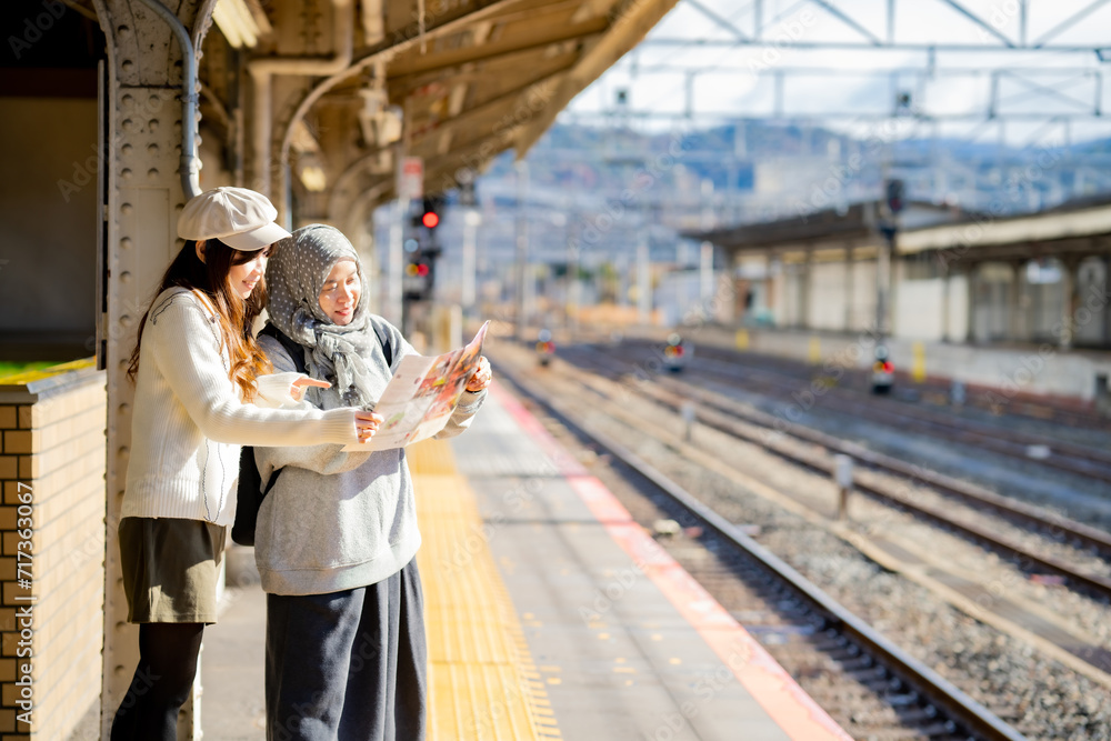 woman girl tourist Two Asian friends but different religions,They were looking at information about preparing to board the train at the train station,She is traveling in Japan. with fun, Japan travel woman girl tourist Two Asian friends but different religions,They were looking at information about preparing to board the train at the train station,She is traveling in Japan. with fun, Japan travel