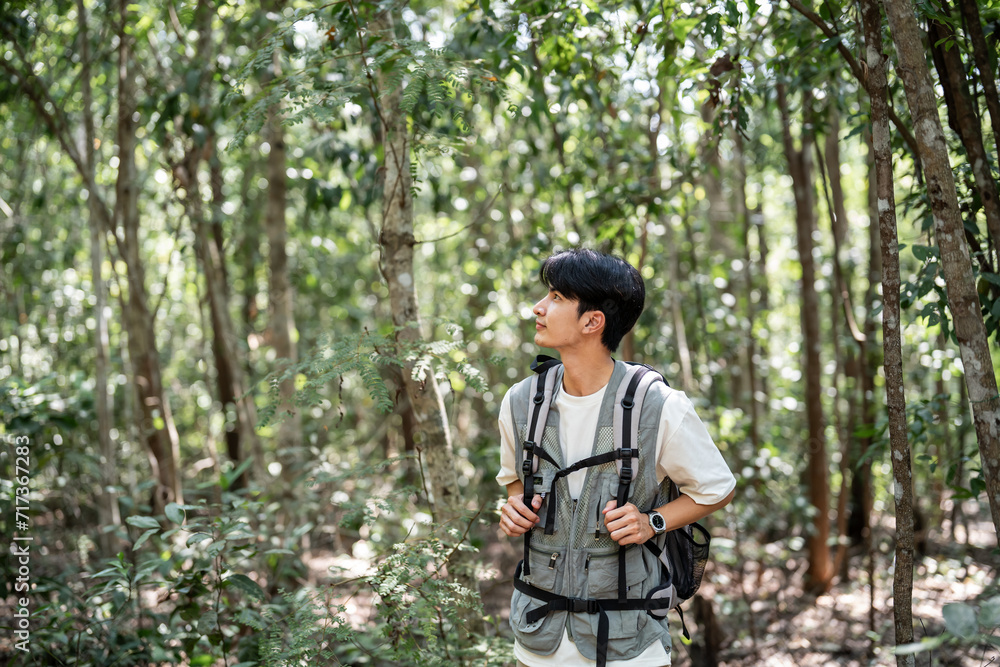 Asian young handsome male backpacker traveling alone in forest wild. 