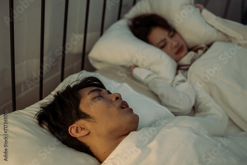 Asian woman feel frustrated from husband snoring while sleep at night. 