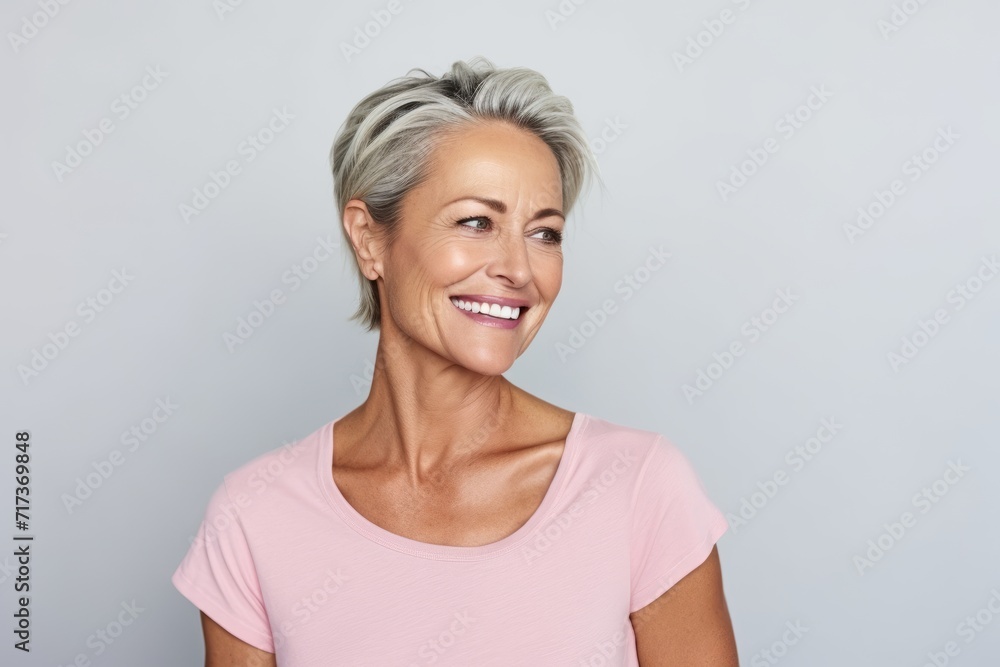 Smiling senior woman looking at the camera against grey background with copy space Smiling senior woman looking at the camera against grey background with copy space
