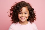 smiling little girl with curly hair looking at camera isolated on pink