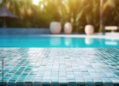 Empty ceramic mosaic table top and blurred swimming pool. 
