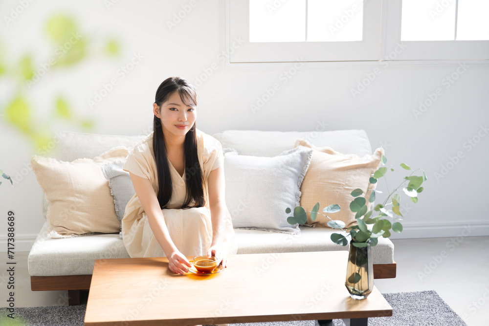 Asian (Japanese) woman with long hair relaxing in her room, drinking tea, looking at the camera Interior and lifestyle images