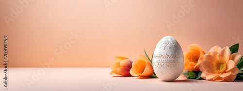 A peach-colored billboard with delicate flowers and an openwork egg, as a symbol of Easter. Free space for text