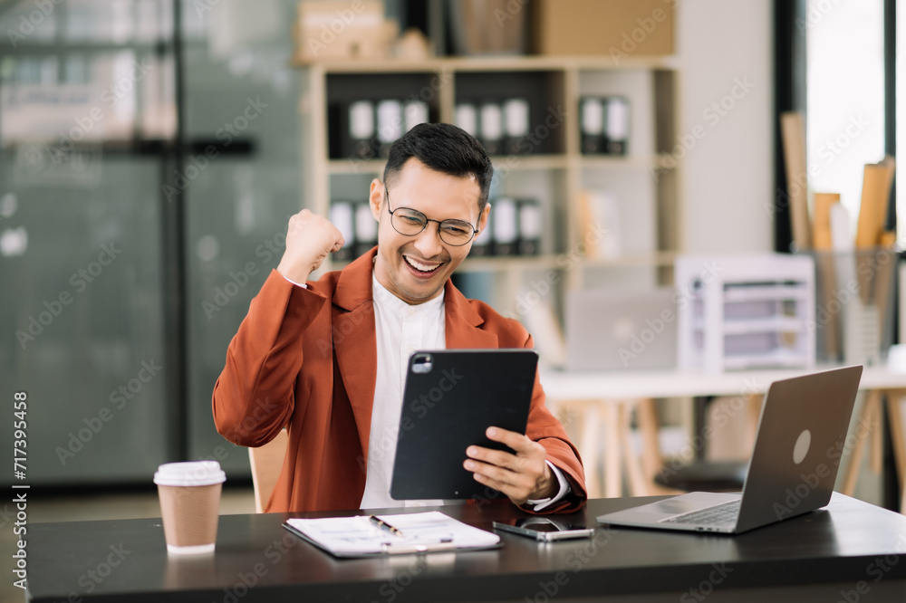 Young attractive man using laptop and tablet while sitting at her working place. Concentrated at work. Young attractive man using laptop and tablet while sitting at her working place. Concentrated at work.