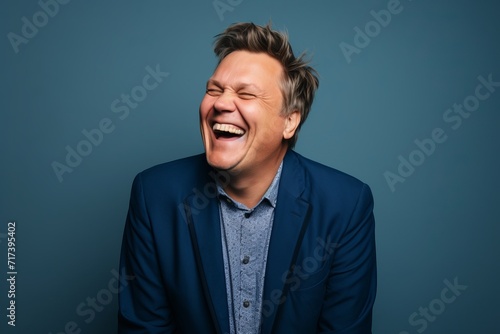 Portrait of a man laughing with closed eyes on a blue background © Inigo