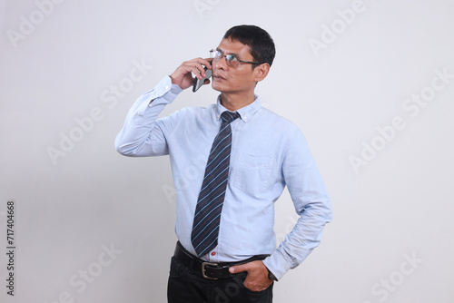 Adult Asian businessman having call on smartphone with business partners or clients