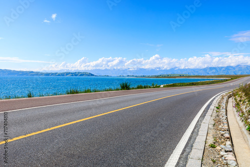 Asphalt highway road and blue lake with mountain nature landscape under blue sky