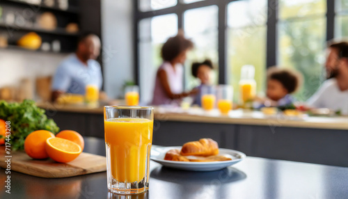 Close up of glass of orange juice on table with family in background