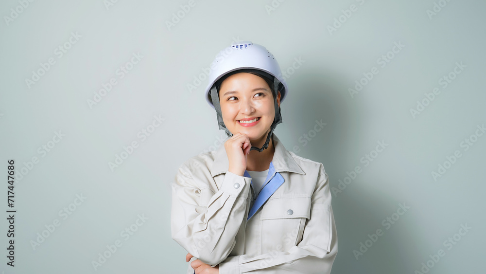 笑顔で考える作業服を着た女性 笑顔で考える作業服を着た女性