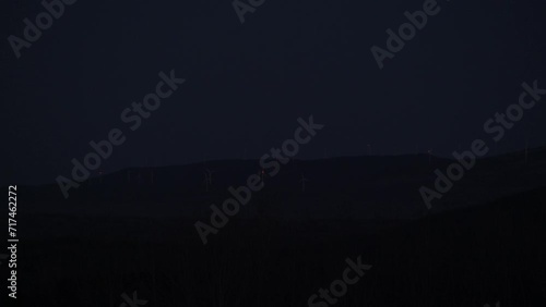Wind turbine mill flashing red light far away on forest hill appalachian mountain at night