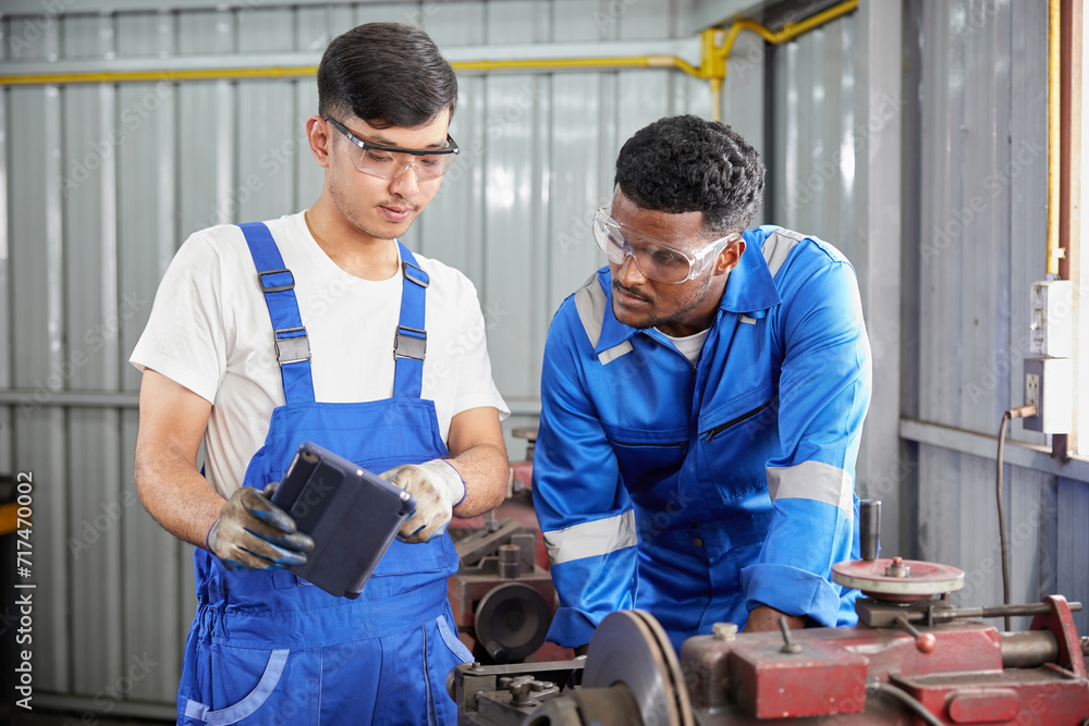 workers or technicians working on tablet beside lathe machine in the factory