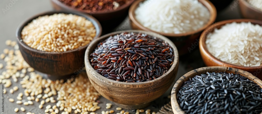Different varieties of grains like Nerone rice, organic forbidden black, brown rice, and white Jasmine Rice displayed on a table top. Different varieties of grains like Nerone rice, organic forbidden black, brown rice, and white Jasmine Rice displayed on a table top.
