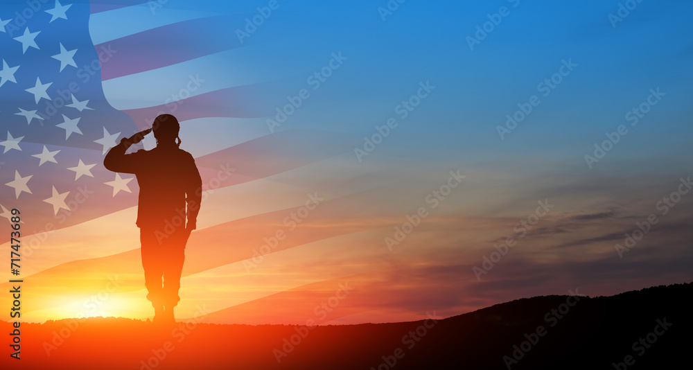 Silhouette of soldier saluting on background of sunset or sunrise and USA flag. Greeting card for Veterans Day, Memorial Day, Independence Day. America celebration.
