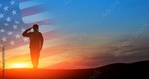 Silhouette of soldier saluting on background of sunset or sunrise and USA flag. Greeting card for Veterans Day  Memorial Day  Independence Day. America celebration.