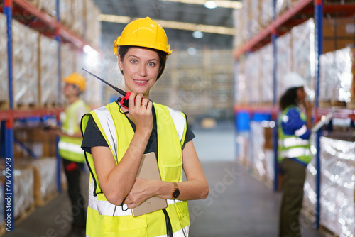 The photograph captures a Western-looking, fair-skinned female warehouse officer striking a confident pose for the camera inside the warehouse. © DG PhotoStock
