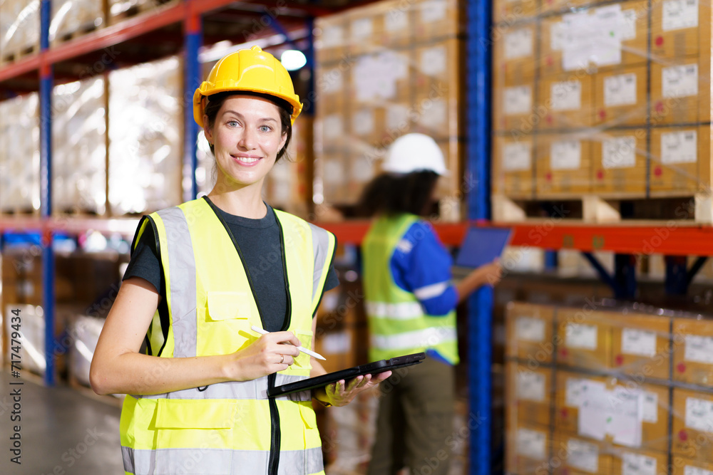 The warehouse officer, who is female, is presently conducting an inspection of the inventory within the warehouse. The warehouse officer, who is female, is presently conducting an inspection of the inventory within the warehouse.
