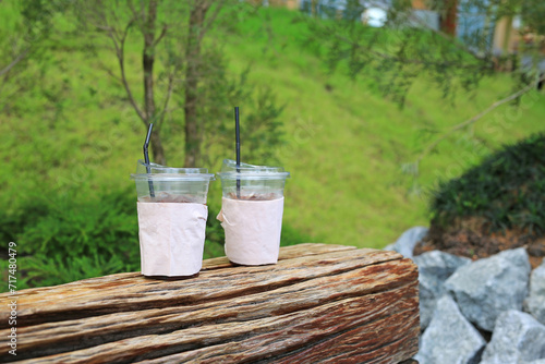 A used plastic drink cups is placed on a wooden bench in the garden.