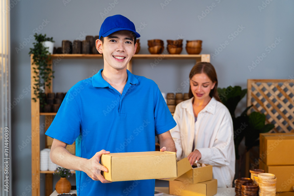 Portrait of delivery man hold the parcel box in his hand after picking up the item from the shopkeeper to deliver it to the customer. he looking at the camera in Small Business and Delivery Concept. Portrait of delivery man hold the parcel box in his hand after picking up the item from the shopkeeper to deliver it to the customer. he looking at the camera in Small Business and Delivery Concept.