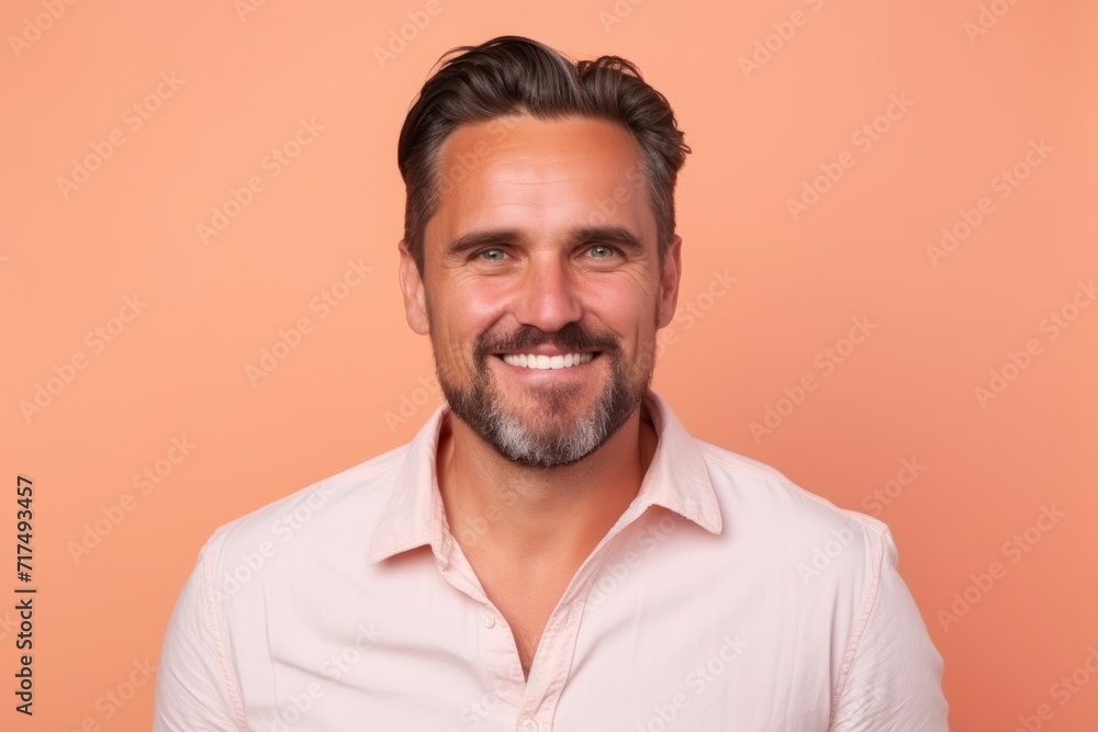 Portrait of a handsome man smiling at the camera while standing against orange background