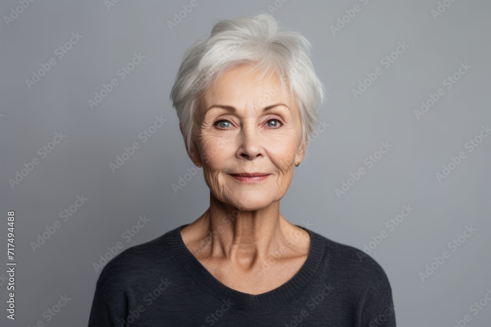 Portrait of a happy senior woman looking at camera over grey background Portrait of a happy senior woman looking at camera over grey background