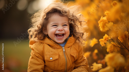 Little child laughing and playing at the park in autumn