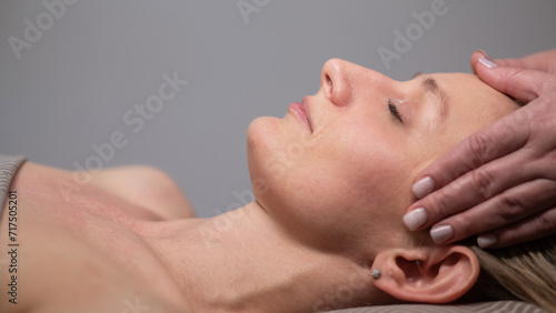 Caucasian woman undergoing head and face massage procedure. 