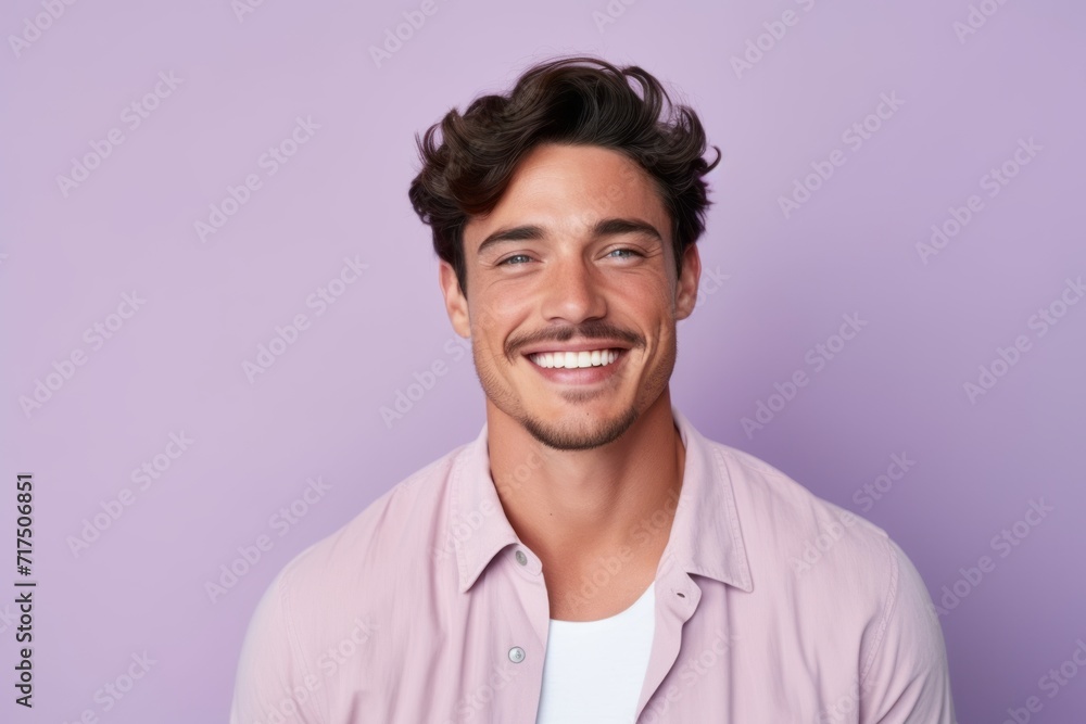 Handsome young man looking at camera and smiling while standing against purple background Handsome young man looking at camera and smiling while standing against purple background