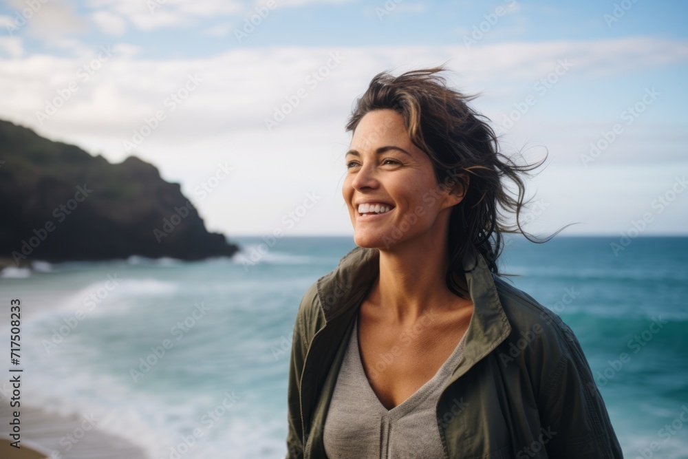 Portrait of smiling woman standing on the beach with ocean in background Portrait of smiling woman standing on the beach with ocean in background