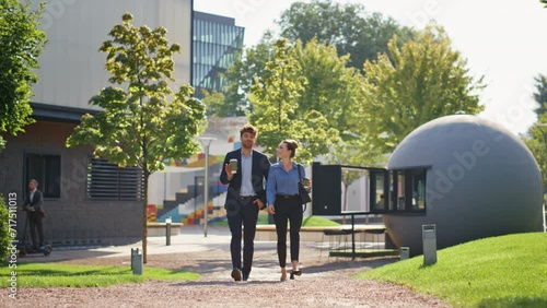 Smiling managers strolling downtown in sunny morning. Business couple talking
