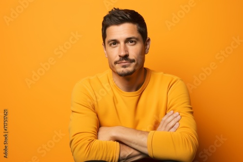 Portrait of handsome young man in yellow sweater on orange background.