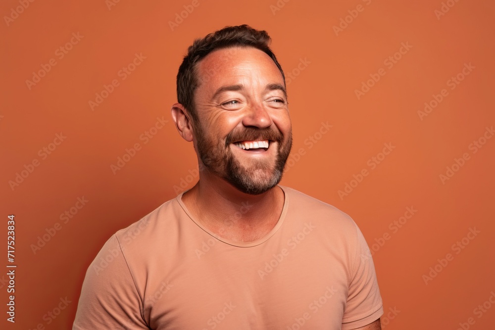 Portrait of a funny man laughing and looking at camera while standing against orange background Portrait of a funny man laughing and looking at camera while standing against orange background