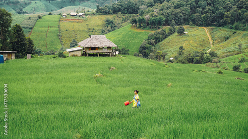 The hill tribe woman in Ban Pa Bong Piang, Chiangmai Province, Thailand. enjoying in rice field with traditional clothes. Woman feel relaxing and enjoying in the meadow and bamboo house