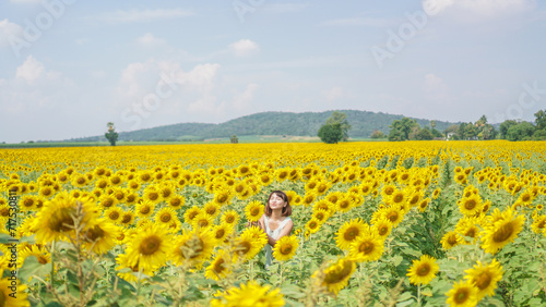 Smile face and short hair asian woman in the field of sunflowers, standing arm raised. Portrait of a beautiful asian woman feeling happy and funny in the sunflower field.