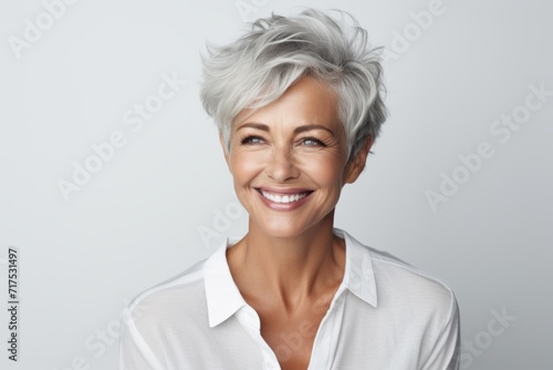Portrait of happy mature businesswoman in white shirt, over grey background