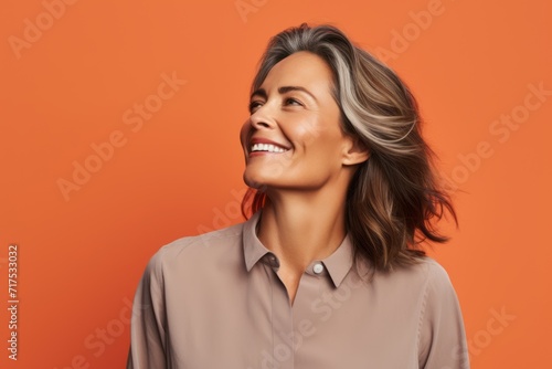 Portrait of smiling mature businesswoman looking up over orange background.