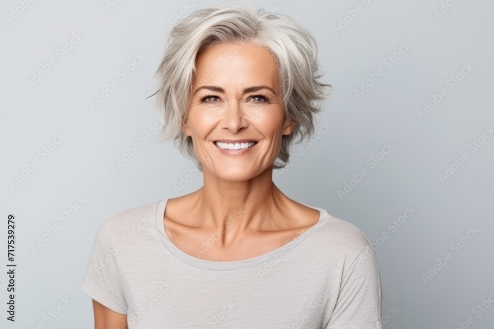 Portrait of a happy mature woman looking at camera over grey background Portrait of a happy mature woman looking at camera over grey background
