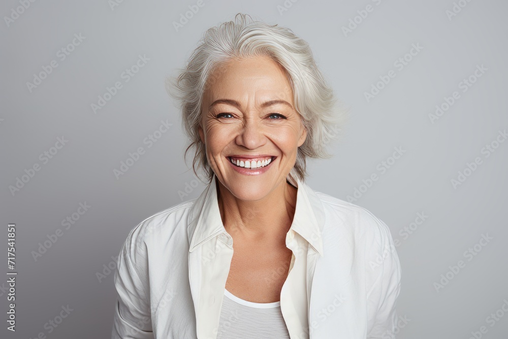 Portrait of a happy senior woman looking at camera over grey background Portrait of a happy senior woman looking at camera over grey background