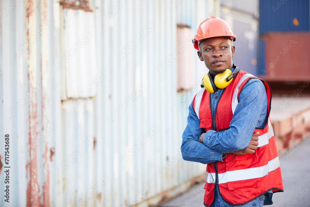 portrait African factory worker or engineer folded arms pose in containers warehouse storage