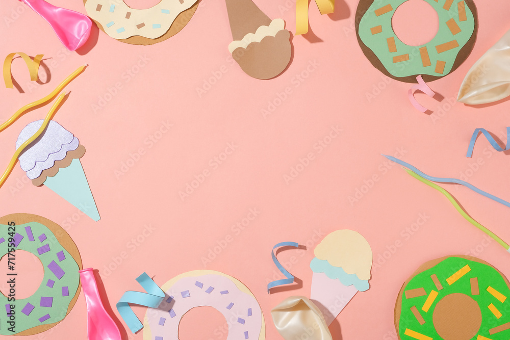 Ice cream and donuts made from colored paper, colored candles, ribbons and uninflated balloons are decorated around the frame with a pink background. Empty space for text design.