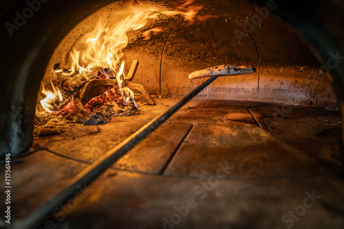 Traditional oven for baking pizza with burning wood and shovel. Neapolitan pizza is finished on a shovel in a brick oven