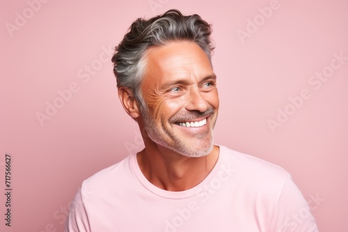 Portrait of a smiling senior man with grey hair, wearing a pink t-shirt.