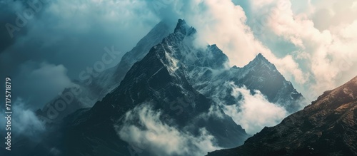 Mysterious minimalist high altitude picturesque mountain landscape with clouds touching large peaks and a spot of light on a mountain. Copy space image. Place for adding text or design photo