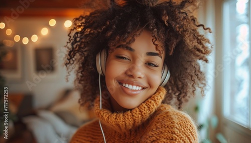 Young african american woman enjoying music in her cozy living room, wearing headphones and dancing with a carefree and joyful expression, capturing the essence of a relaxed and stylish lifestyle.