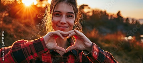 In this heartwarming close up a young woman forms a heart shape with her hands radiating love and positivity The focus is on her hands which convey a heartfelt message offering a connection tha photo